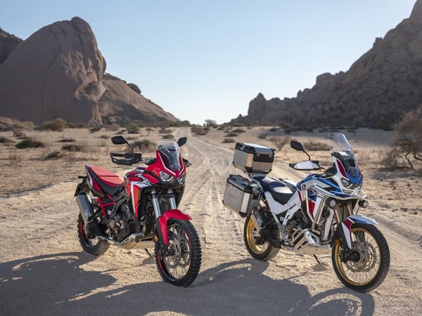 A Honda Africa Twin Standard model and Adventure Sports side by side in the desert.