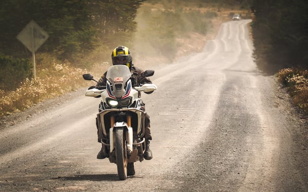 Rider in Patagonia on a Honda Africa Twin blazing down a gravel road.