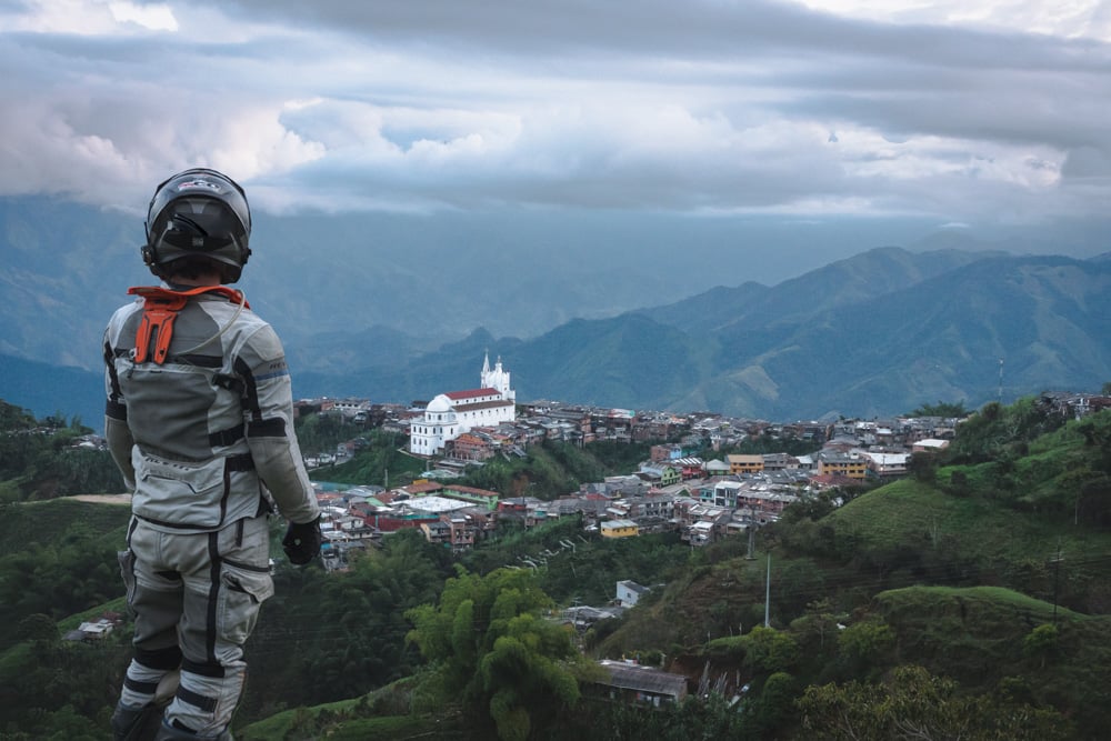 Full motorcycle gear Ricardo overlooking the Andes with a small church on one of the hills