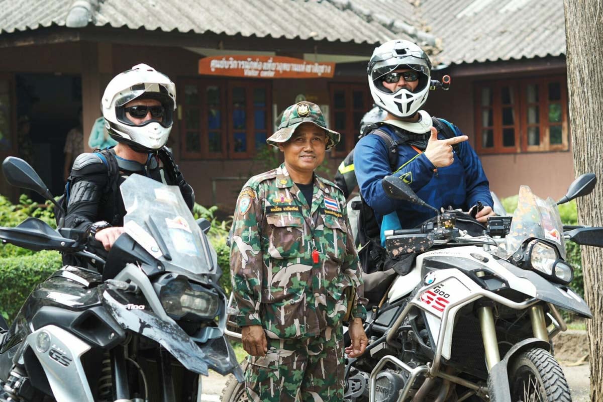 A couple riders hanging out with the local military in Thailand
