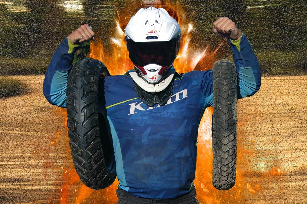 Eric flexing his muscles while holding a pair of adventure motorcycle tires. 