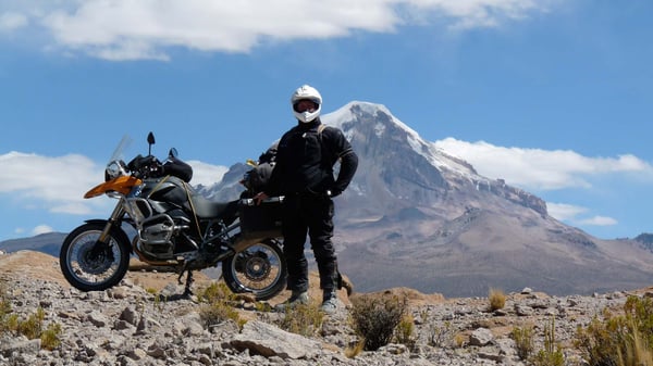 Eric posing with his bike in front of a massive volcano mountain