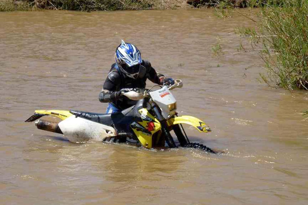Dirt biker trying to get his bike out of a river.