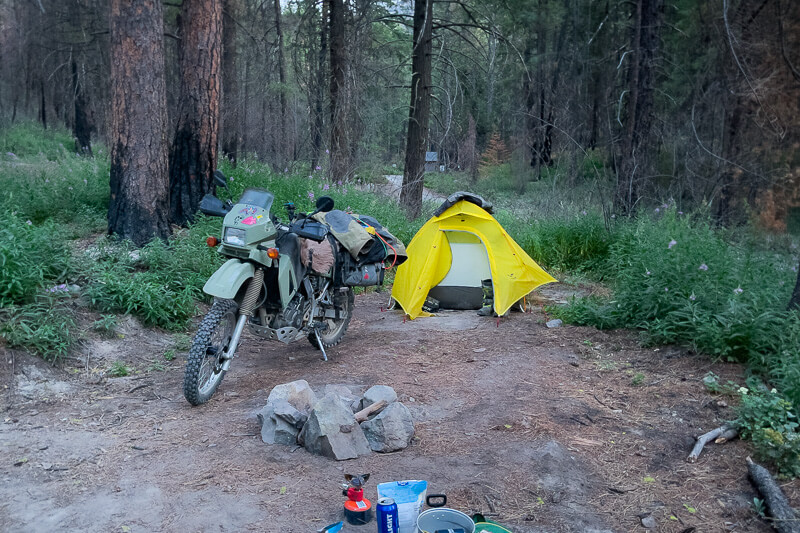 Garrett's KLR 650 camping in the woods with his high capacity tusk highland x2 rackless adventure motorcycle soft luggage.
