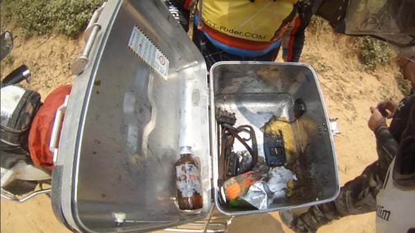 An opened hard motorcycle case with all of it's insides shaken and in scattered