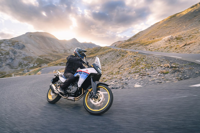 Adv rider riding the brand new 2023 Honda Transalp through some twisties during sunset.