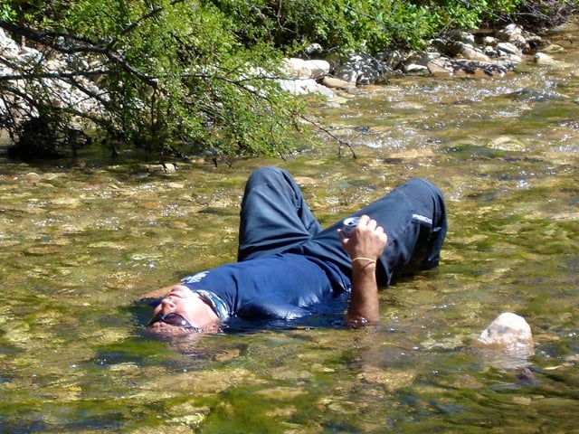 Adventure rider laying in the cool river on a hot day.