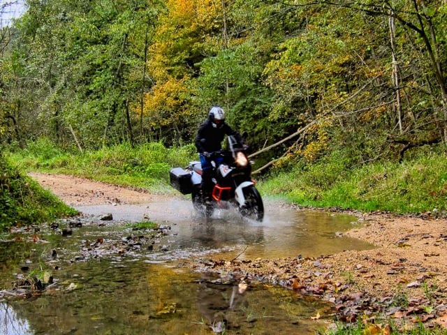 ADV rider blazing through a water crossing on a bike KTM 1090 Adventure motorcycle.