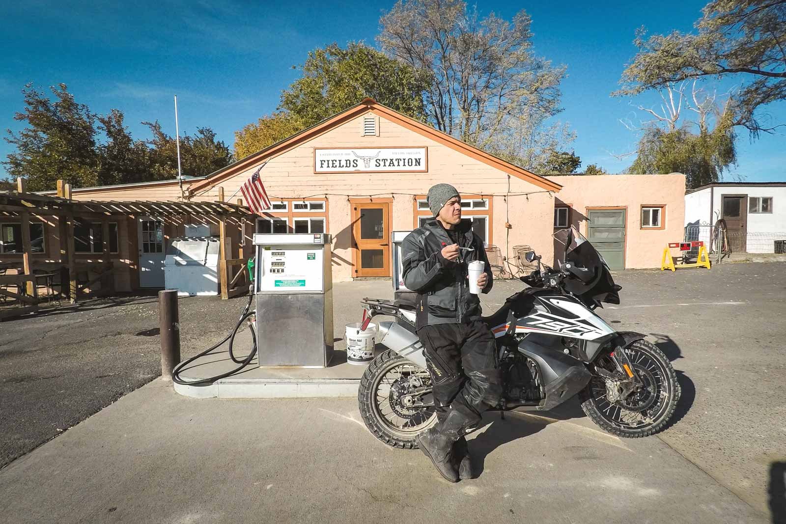 Garrett eating ice cream while leaning on the KTM 790 Adventure in front of fields station gas station