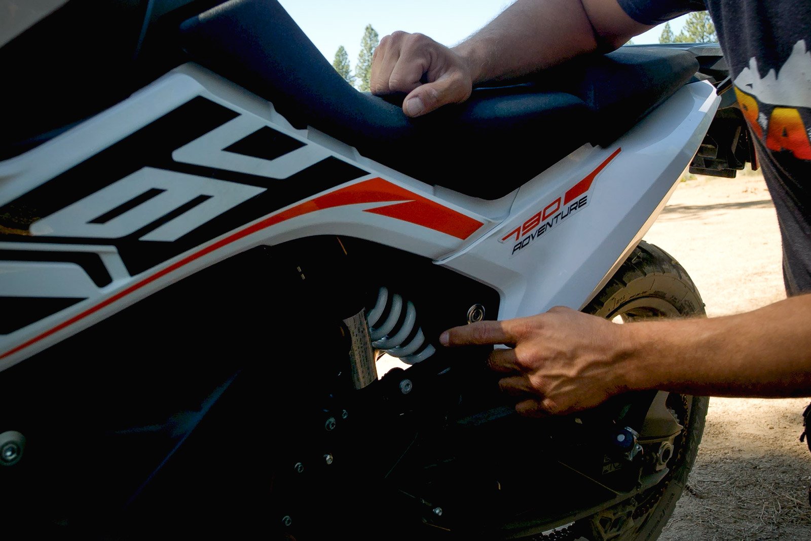 Eric down low and pointing towards the ktm 790 adventure s's suspension