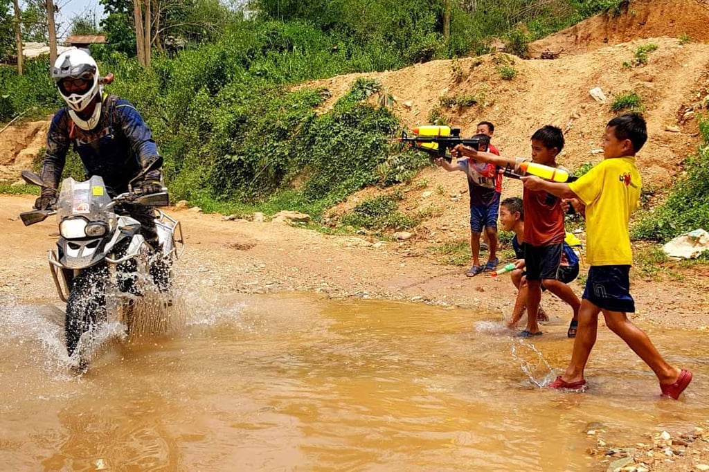 Eric getting cooled down by water as some kids use super soakers to spray Eric while he's riding by on his motorcycle.. 