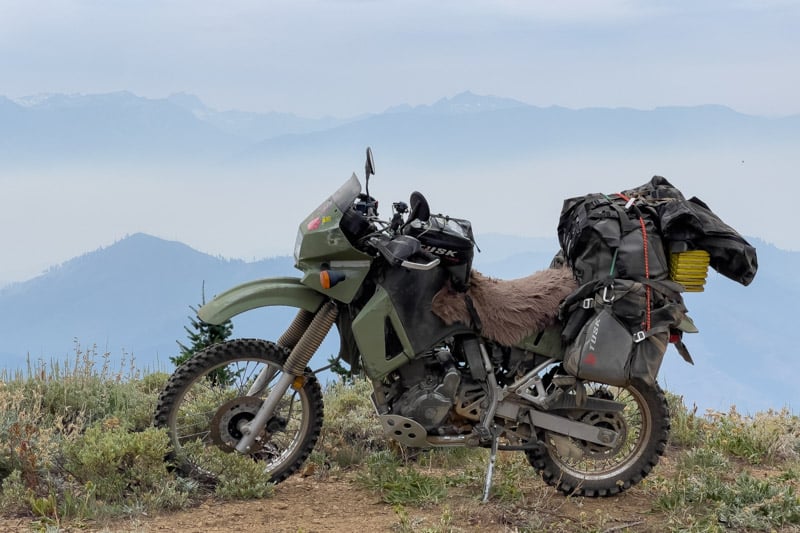 Garrett's KLR 650 in the mountains with the Tusk Highland X2 Rackless adventure motorcycle soft luggage attached.