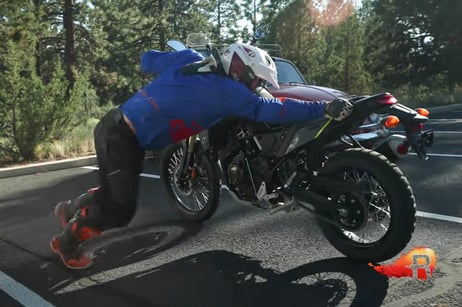 Eric pushing a bike backwards out of a parking lot uphill.