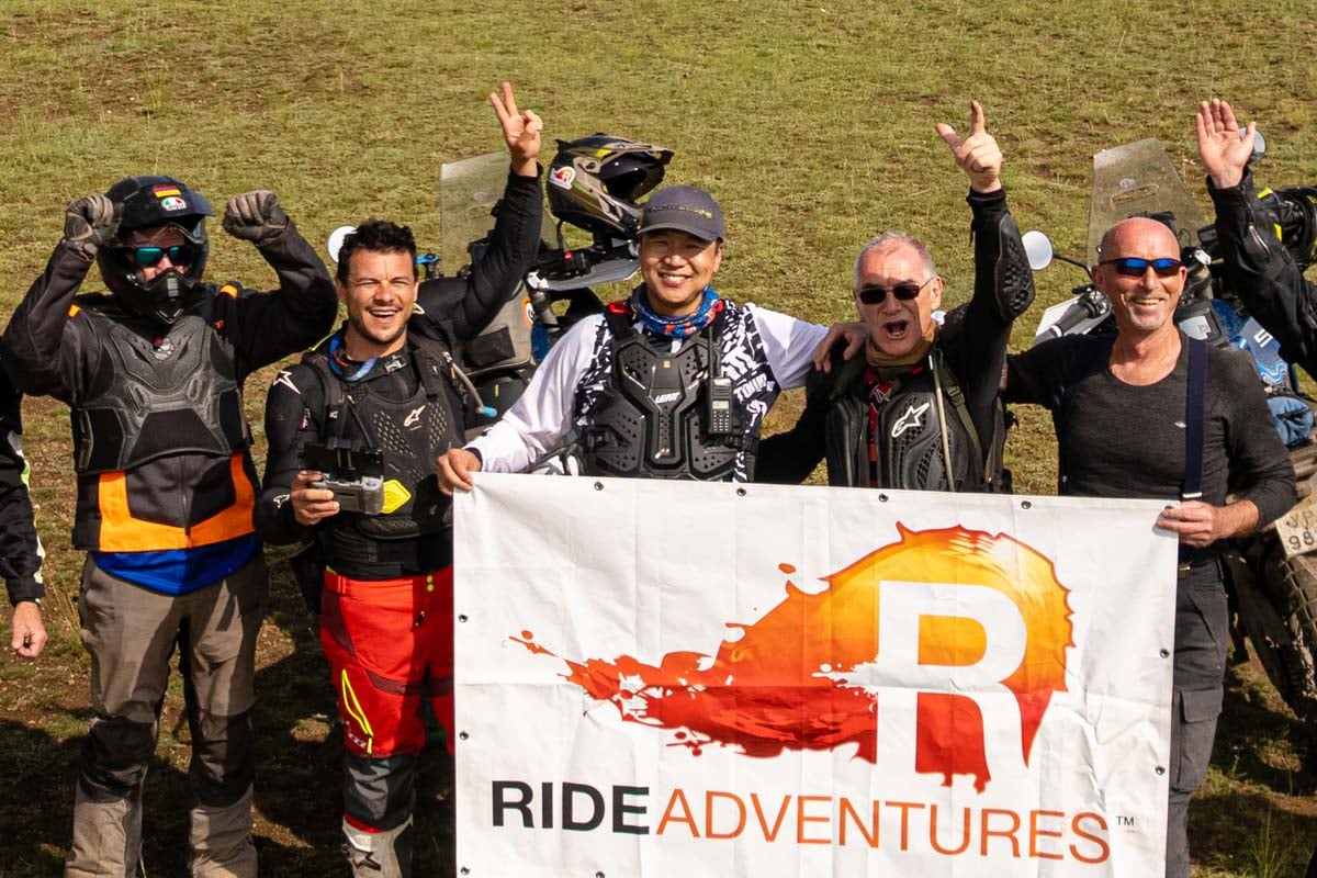 team poses with smiles cheering laughter in front of RIDE logo banner in Mongolia-1