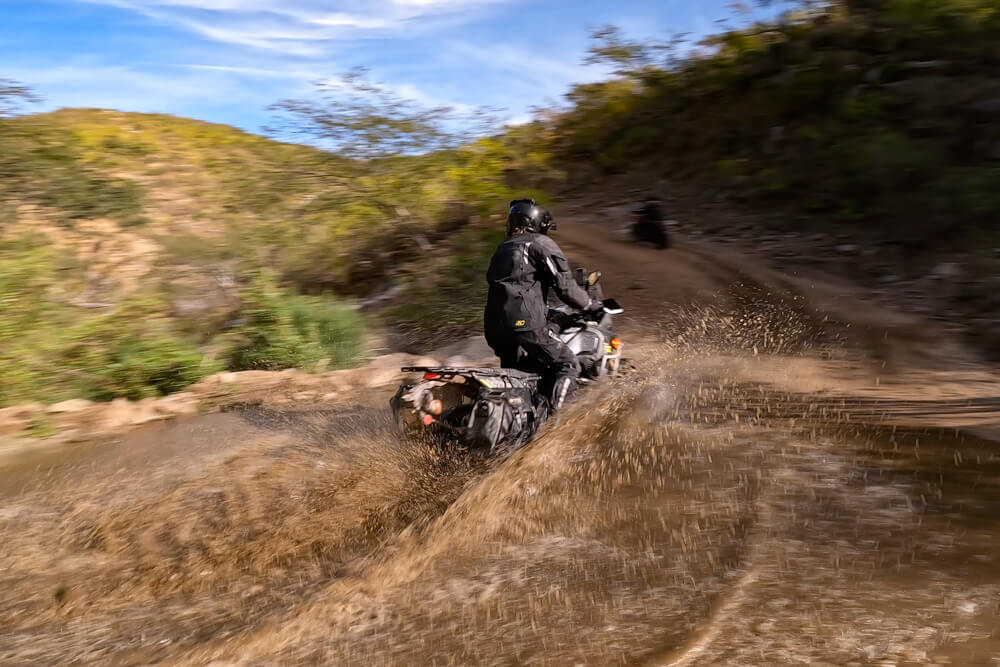 Tyler riding through a puddle in Baja while wearing the Krios Karbon helmet.