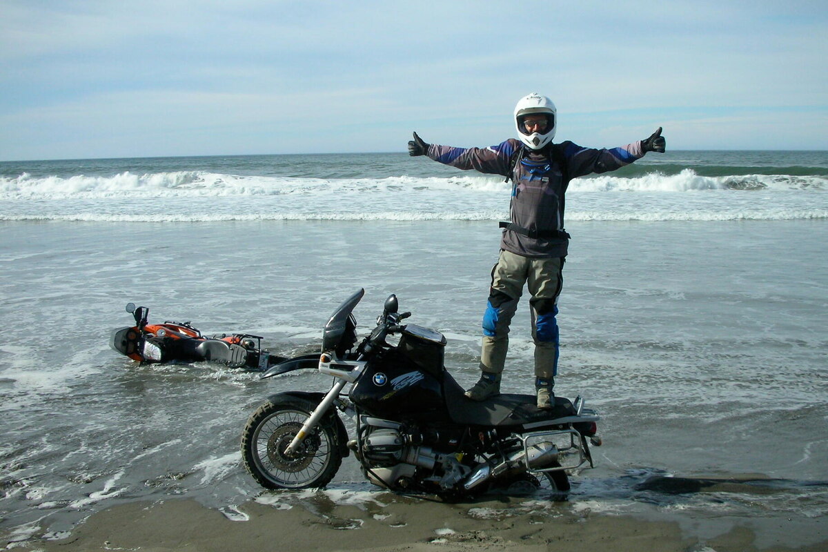two motorcycles one the beach rider on top of one and other under water