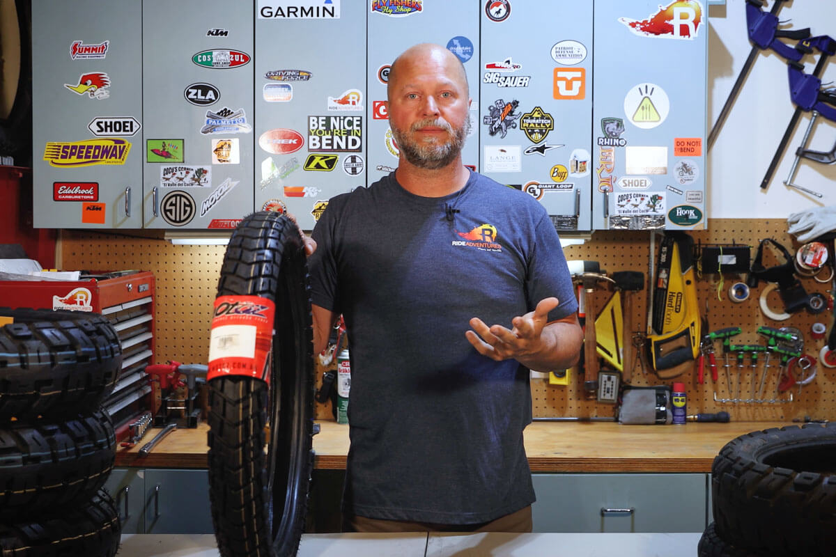 Eric at his studio holding an adventure motorcycle tire explaining which tire is the right one for you.