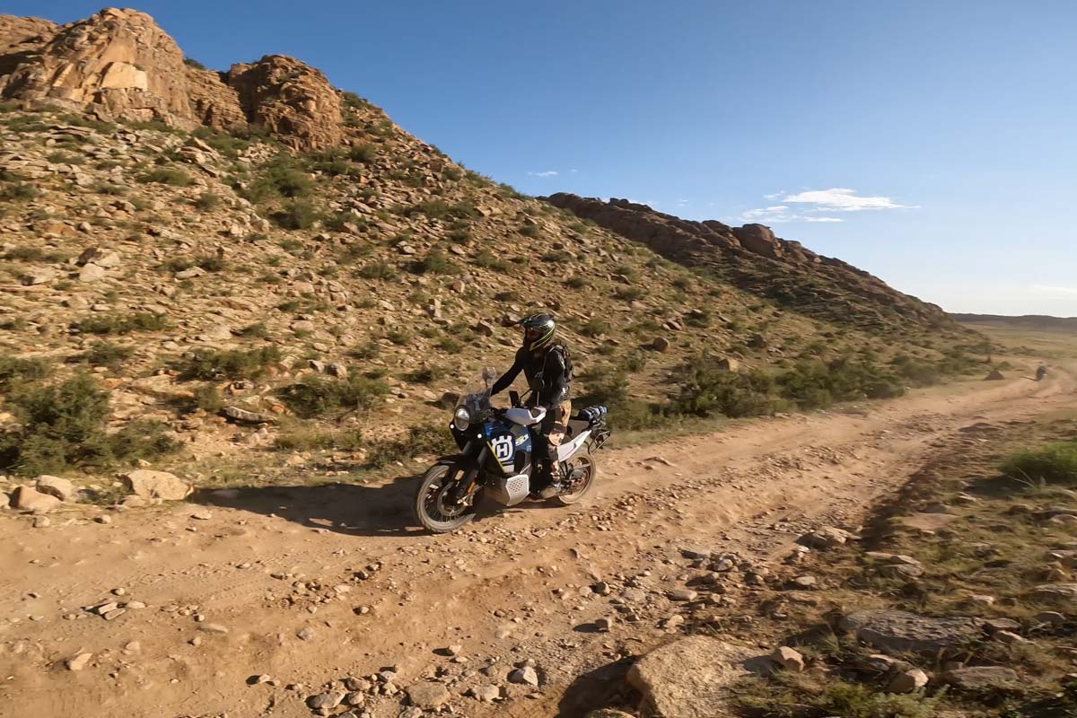 dermot riding between the hills on a rocky trail mongolia